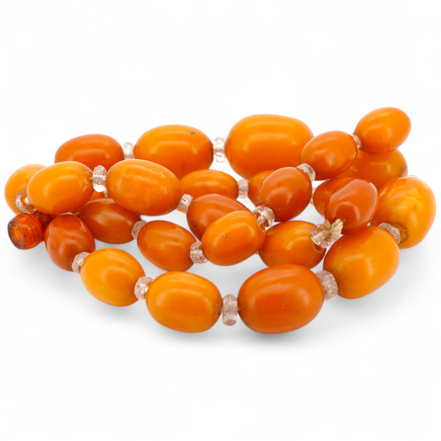 A single strand graduated oval amber bead necklace, with paste spacers, 44cm, gross weight 26 grams, one clasp missing.